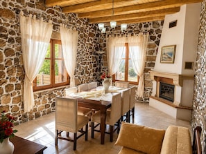 A stone-walled room with a fireplace, dining table, chairs, and curtains. - Villa Maria Christina With Private Pool in Crete (Faistos)