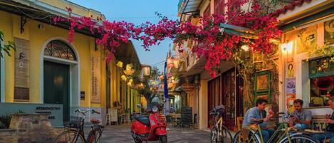 A narrow street with buildings on either side, bicycles parked along the sides, and a red scooter in the center.