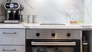 A kitchen with a built-in oven, a coffee machine, and a marble backsplash. - Studio 4 Kalamata - Bright Escape in the Centre (Kalamata)