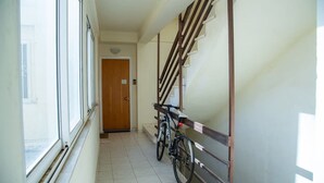 A narrow hallway with a wooden staircase, a bicycle, and a door at the end. - Studio 4 Kalamata - Bright Escape in the Centre (Kalamata)
