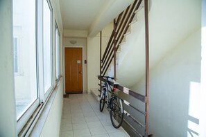 Ein schmaler Flur mit einer Holztreppe, einem Fahrrad und einer Tür am Ende.