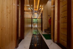 Un pasillo de madera con piso reflectante, puertas a ambos lados y un candelabro.