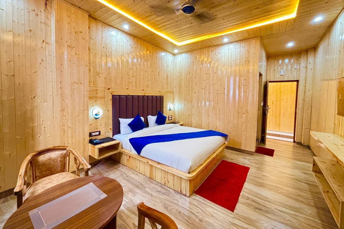 A wooden-paneled room with a bed, a desk, a chair, and a red rug.