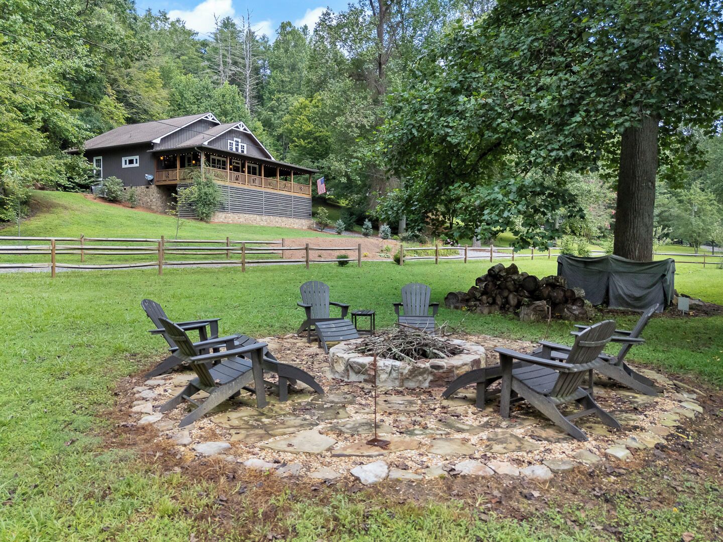 A lodge with a stone fire pit and Adirondack chairs in the yard.