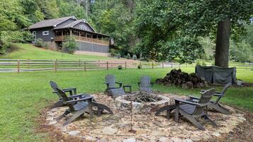 A lodge with a stone fire pit and Adirondack chairs in the yard.