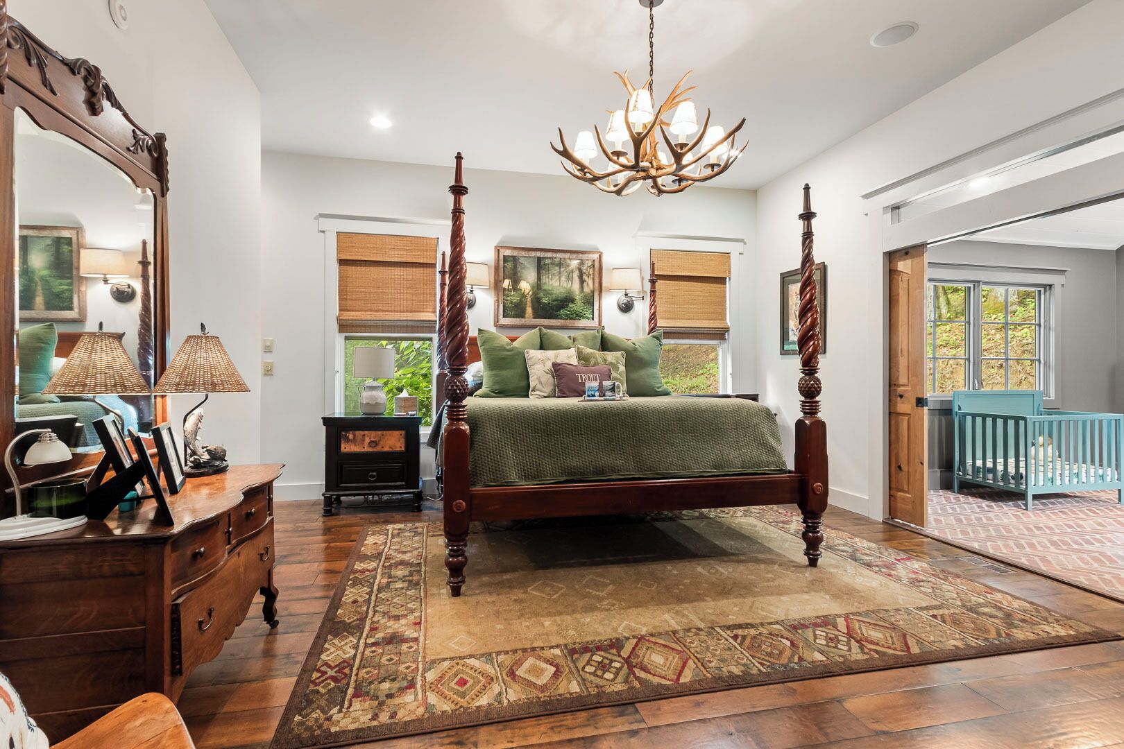 A four-poster bed with a chandelier, a large mirror, and a view of the outdoors through a window.
