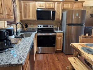 Eine Küche mit Holzschränken, einem Edelstahlkühlschrank, einer Mikrowelle, einem Backofen und einem Spülbecken.