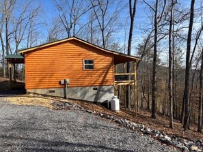 A wooden cabin with a porch, a small window, and a water tank. - Cozy Wooded Retreat! (Murphy)