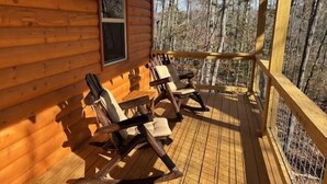 A wooden cabin with a porch, rocking chairs, and a window overlooking a forest. - Cozy Wooded Retreat! (Murphy)