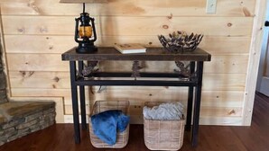 A wooden wall with a table featuring a lamp, a decorative bowl, and two baskets. - Cozy Wooded Retreat! (Murphy)