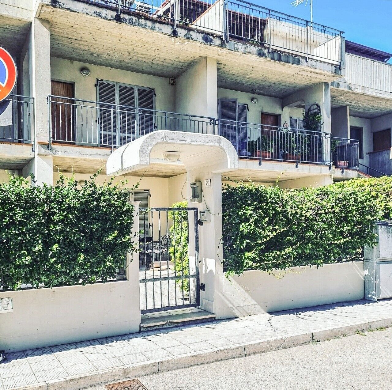 Un immeuble à plusieurs étages, doté d’une entrée sécurisée par un portail, de balcons et surplombant un ciel dégagé.