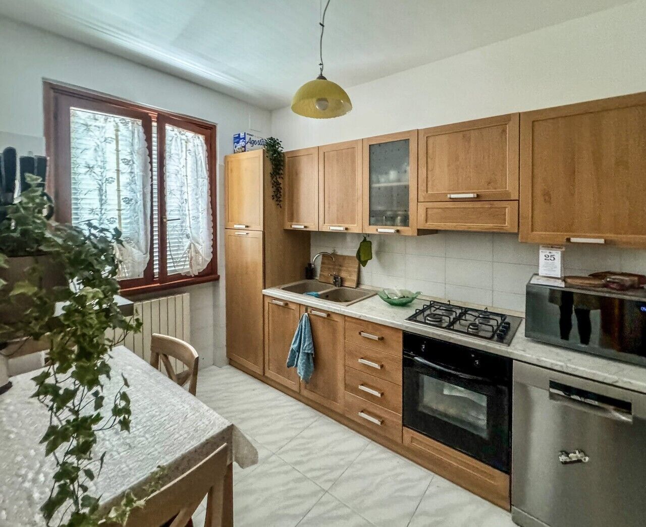 A kitchen with wooden cabinets, a gas stove, a sink, and a microwave.