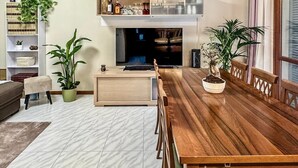Una sala de estar moderna con una mesa de comedor de madera, un sofá, un televisor y una chimenea.