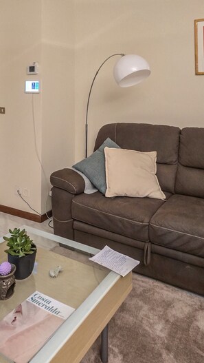 A brown leather sofa with two pillows, a white floor lamp, a glass coffee table with a plant, a small bag, and a piece of paper. - Villa Garden - Porto San Giorgio (Porto San Giorgio)