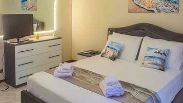 Une chambre à coucher avec un lit, des tables de chevet, une télévision et des œuvres d’art accrochées au mur.