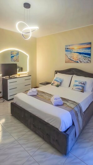 A bedroom with a bed, bedside tables, a TV, and artwork on the wall. - Villa Garden - Porto San Giorgio (Porto San Giorgio)
