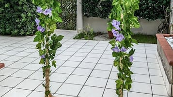 Une balançoire en bois suspendue à une corde, entourée d’une terrasse carrelée.