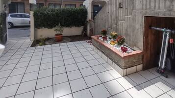 Een betegeld terras met potplanten en een scooter.