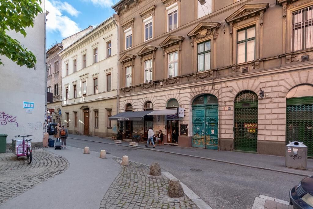 A street with buildings, a coffee stand, and a green gate.