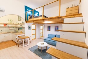 A compact living space with a kitchenette, a dining area, a sofa, and a loft bedroom with a bed. - Blue & Wood Loft Stay in Budapest Soul (Budapest)