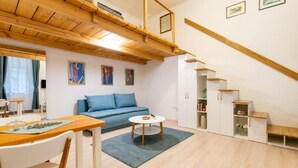 Ein modernes Interieur mit Holzboden, einem blauen Sofa, einem Esstisch und einer Treppe.
