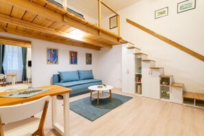 A modern interior with a wooden ceiling, a blue sofa, a dining table, and a staircase. - Blue & Wood Loft Stay in Budapest Soul (Budapest)