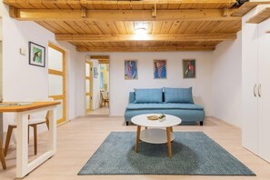 A room with a wooden ceiling, a blue sofa, a white table, and artwork on the walls. - Blue & Wood Loft Stay in Budapest Soul (Budapest)