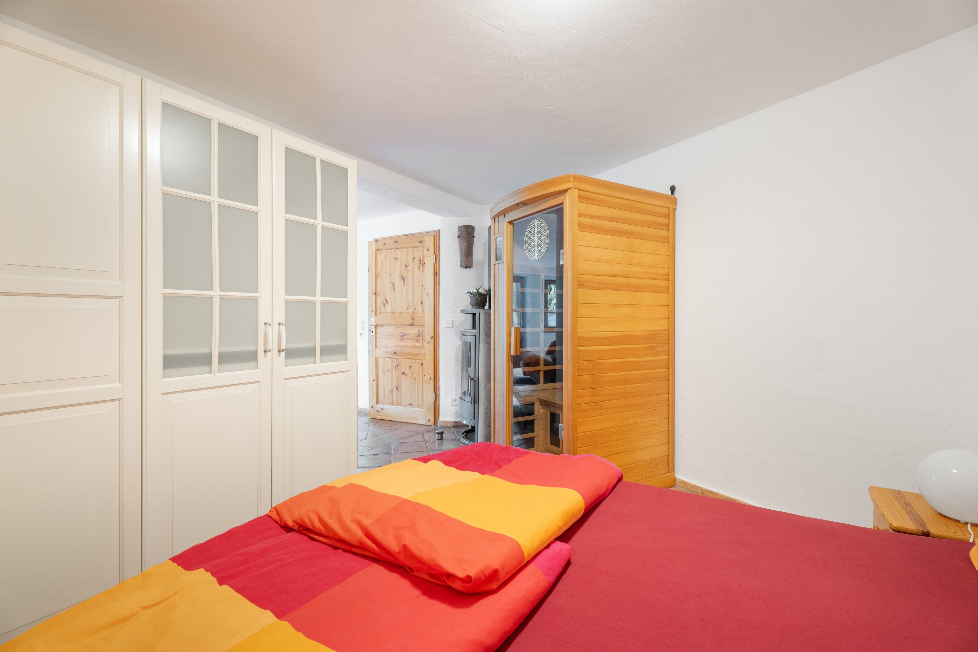 A bedroom with a bed, a wardrobe, and a wooden cabinet.
