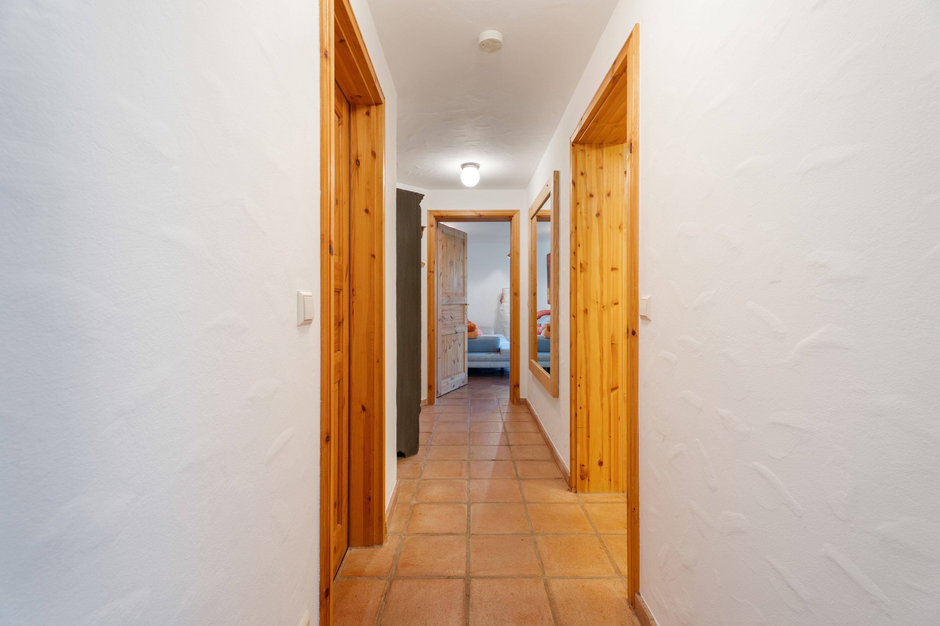 Un couloir étroit, avec des portes en bois donnant sur une chambre à coucher.