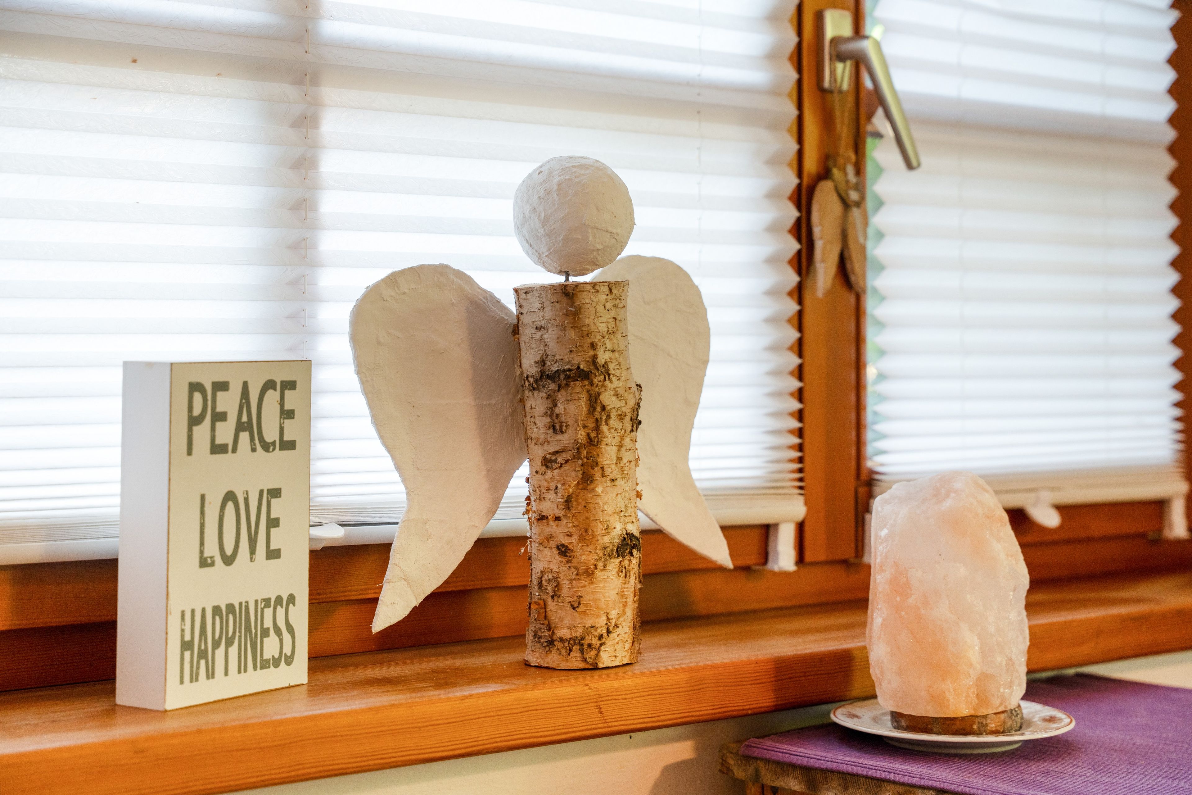 Uno scaffale in legno con un cartello che riporta la scritta 'PEACE LOVE HAPPINESS' e un cristallo su un piatto.