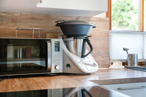 A kitchen with a microwave, coffee maker, and a window with blinds.
