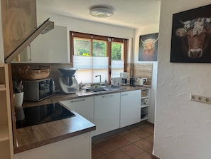 A kitchen with a microwave, coffee maker, toaster, and a window with blinds. - Apartment "Wusslers Bach-Idyll" with Shared Terrace, Garden and Wi-Fi (Gengenbach)