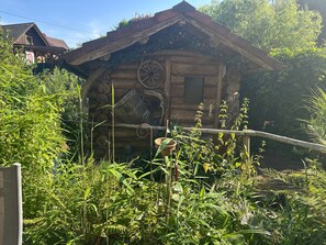 A rustic wooden cabin with a sloped roof, surrounded by dense greenery. - Apartment "Wusslers Bach-Idyll" with Shared Terrace, Garden and Wi-Fi (Gengenbach)