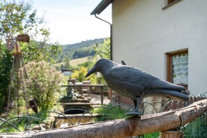 A bird statue on a wooden post with a wire fence in a garden setting.