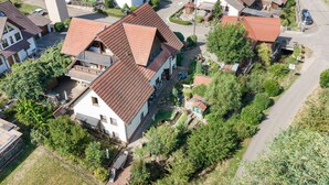 Een woongebied met huizen met schuine daken, omringd door groen en een kronkelende weg.