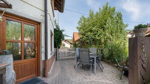 Een terras met een houten deur, een metalen hek en een tafel met stoelen.