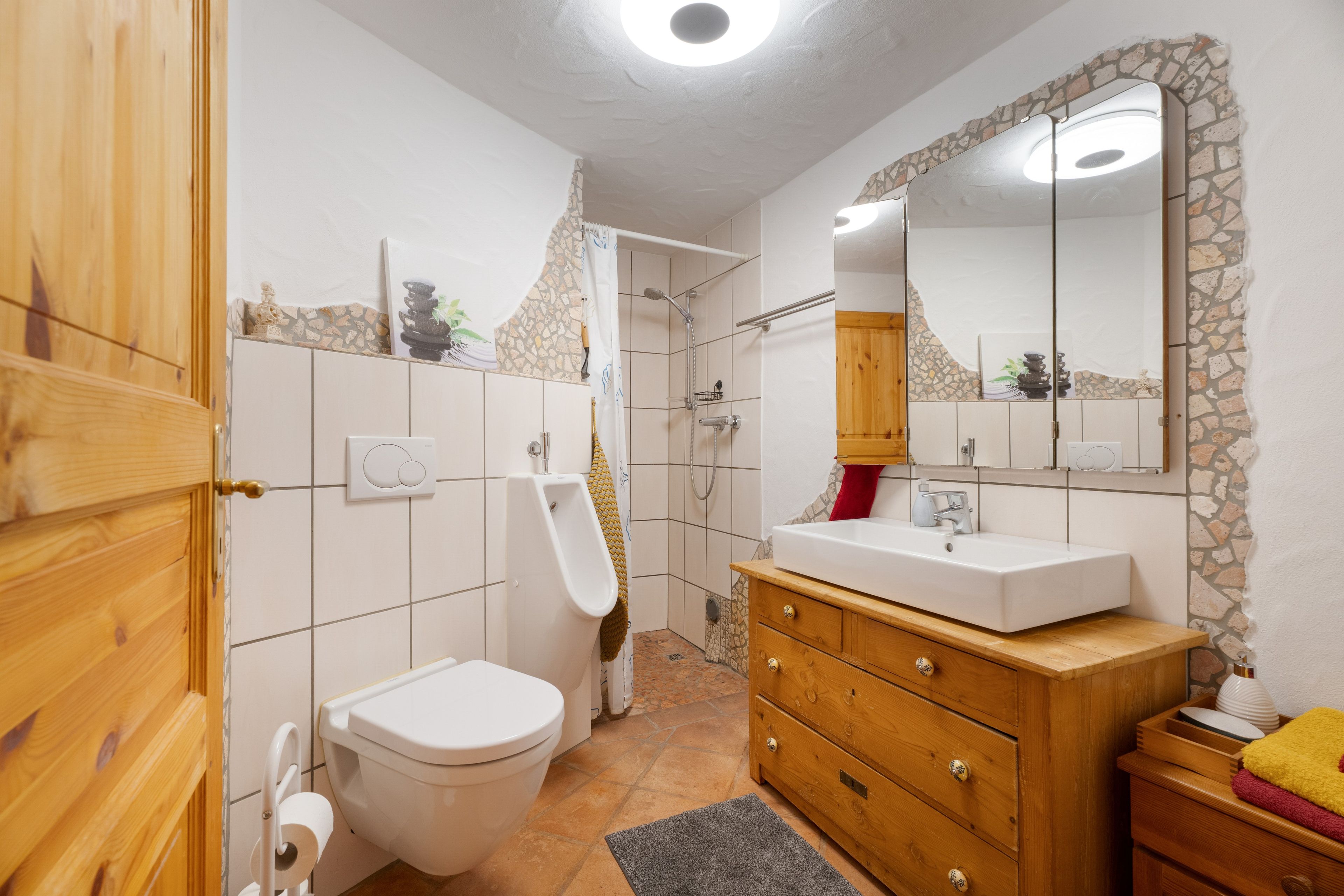 Un baño con inodoro, bidé, ducha y un tocador de madera con lavamanos.