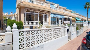Un bâtiment de style méditerranéen doté de balcons, de grandes fenêtres et d’une entrée fermée par un portail.