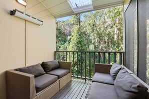 Ein Balkon mit Korbmöbeln und Blick auf dichtes Grün.