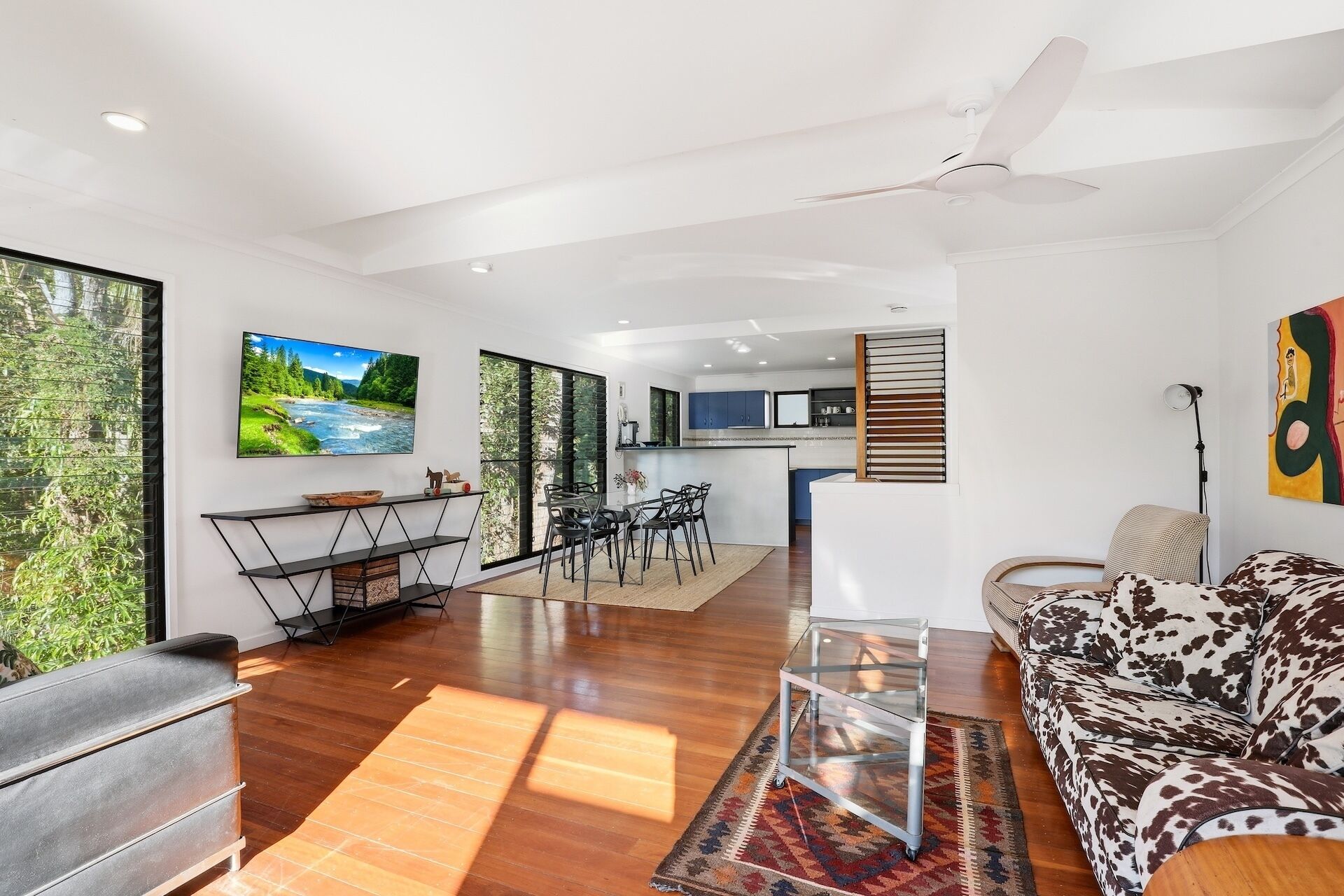 A modern living room with a sofa, a dining area, and a kitchen in the background.