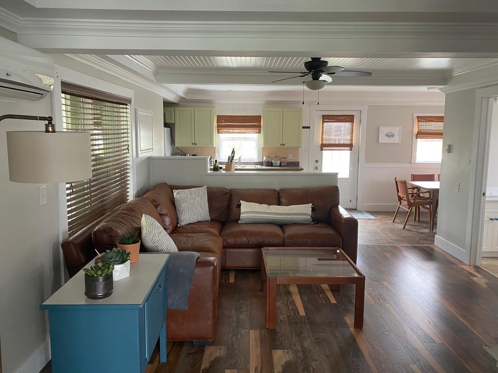 A living room with a brown leather sofa, a blue side table, and a glass coffee table.