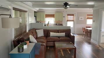 A living room with a brown leather sofa, a blue side table, and a glass coffee table.