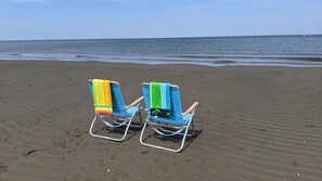 Deux chaises de plage avec des serviettes, sur une plage de sable.