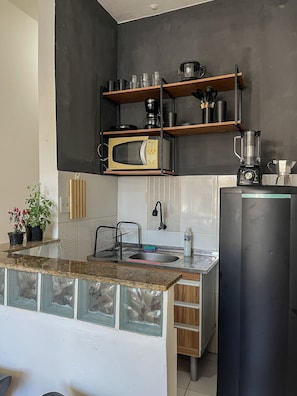 A kitchen with a microwave, coffee maker, blender, and a sink with a faucet. - Studio vista mar pertinho da praia (Rio de Janeiro)