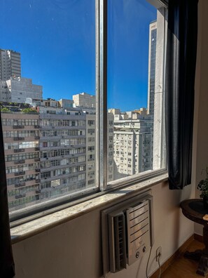 Una ventana con vistas a edificios altos, un radiador y una cortina.