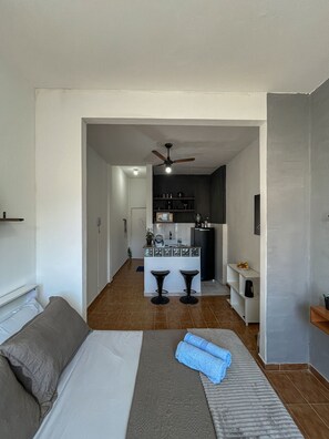 A hotel room with a bed, a small kitchenette, and a ceiling fan. - Studio vista mar pertinho da praia (Rio de Janeiro)