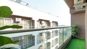 A balcony with a glass railing, a potted plant, and a view of neighboring buildings.