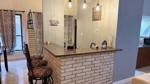 A kitchen with a brick island, hanging pendant lights, and a decorative sign.