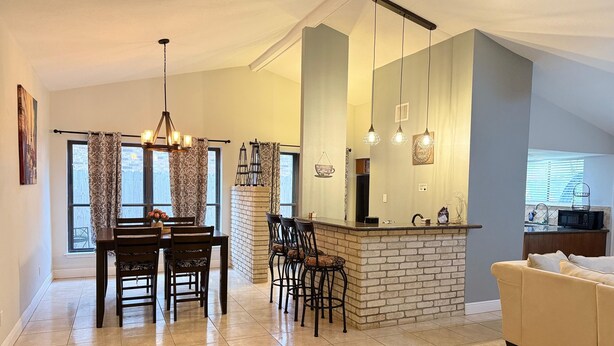 A spacious living area with a dining table, chairs, a kitchen island, and a sofa.