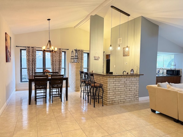 A spacious living area with a dining table, chairs, a kitchen island, and a sofa.